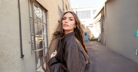 Volume Eyelash Extensions worn by stylish woman in brown jacket walking down urban alleyway.