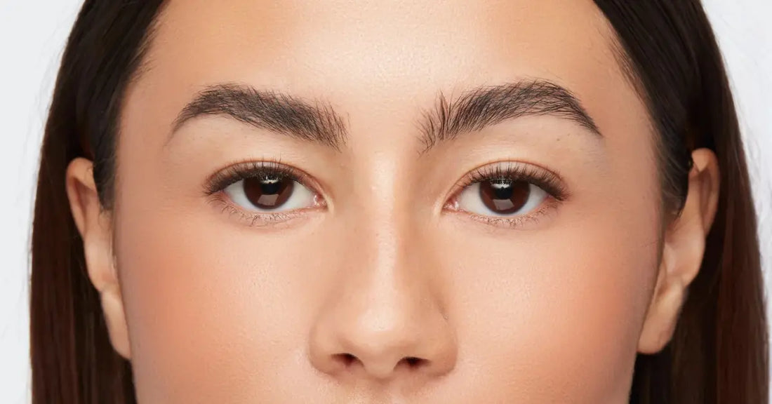 Everyday lash extensions shown on a close-up of natural lashes and full brows with minimal makeup.