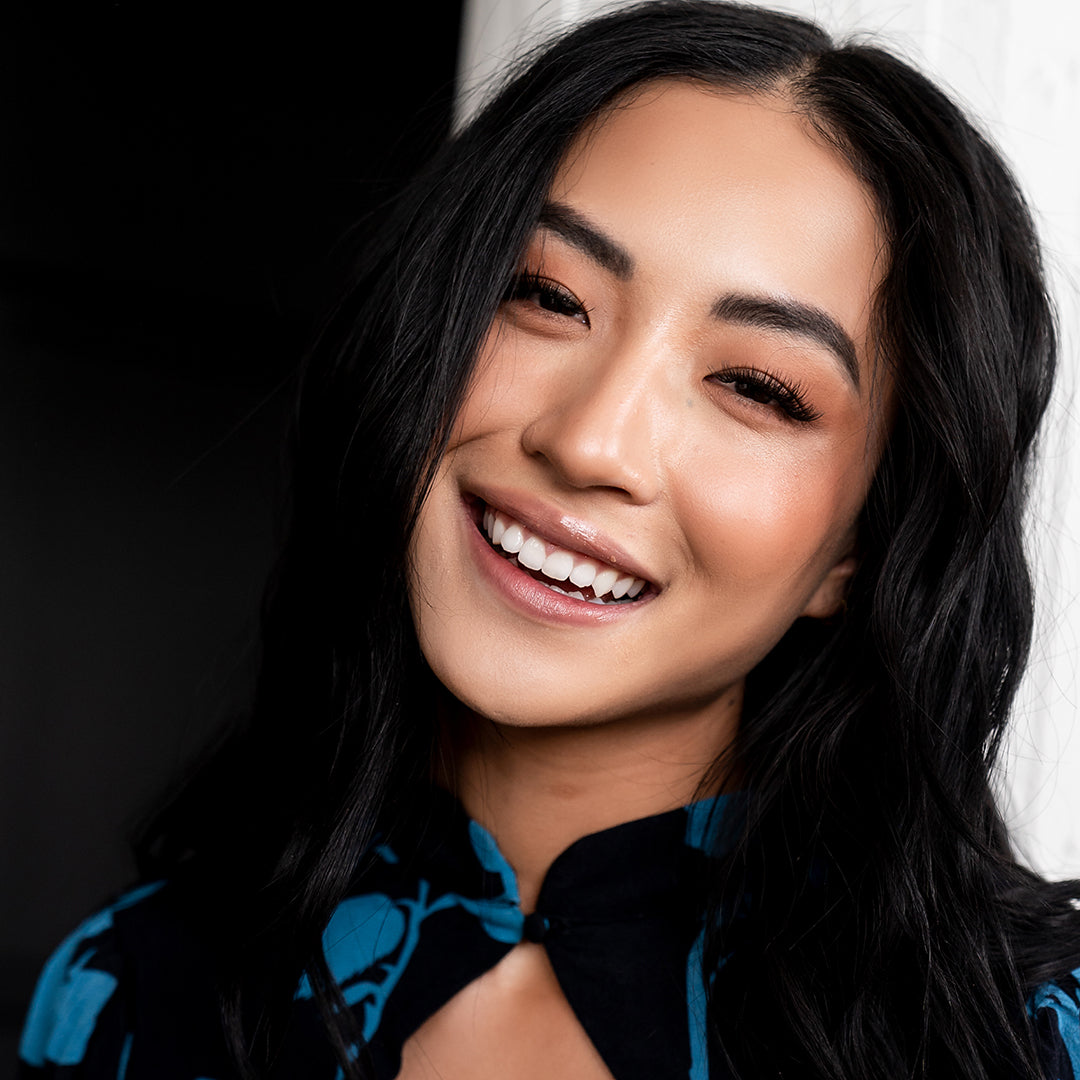 Classic cat eyelash extensions styled on smiling woman, creating a flared, lifted effect with longer lashes at the outer corners.