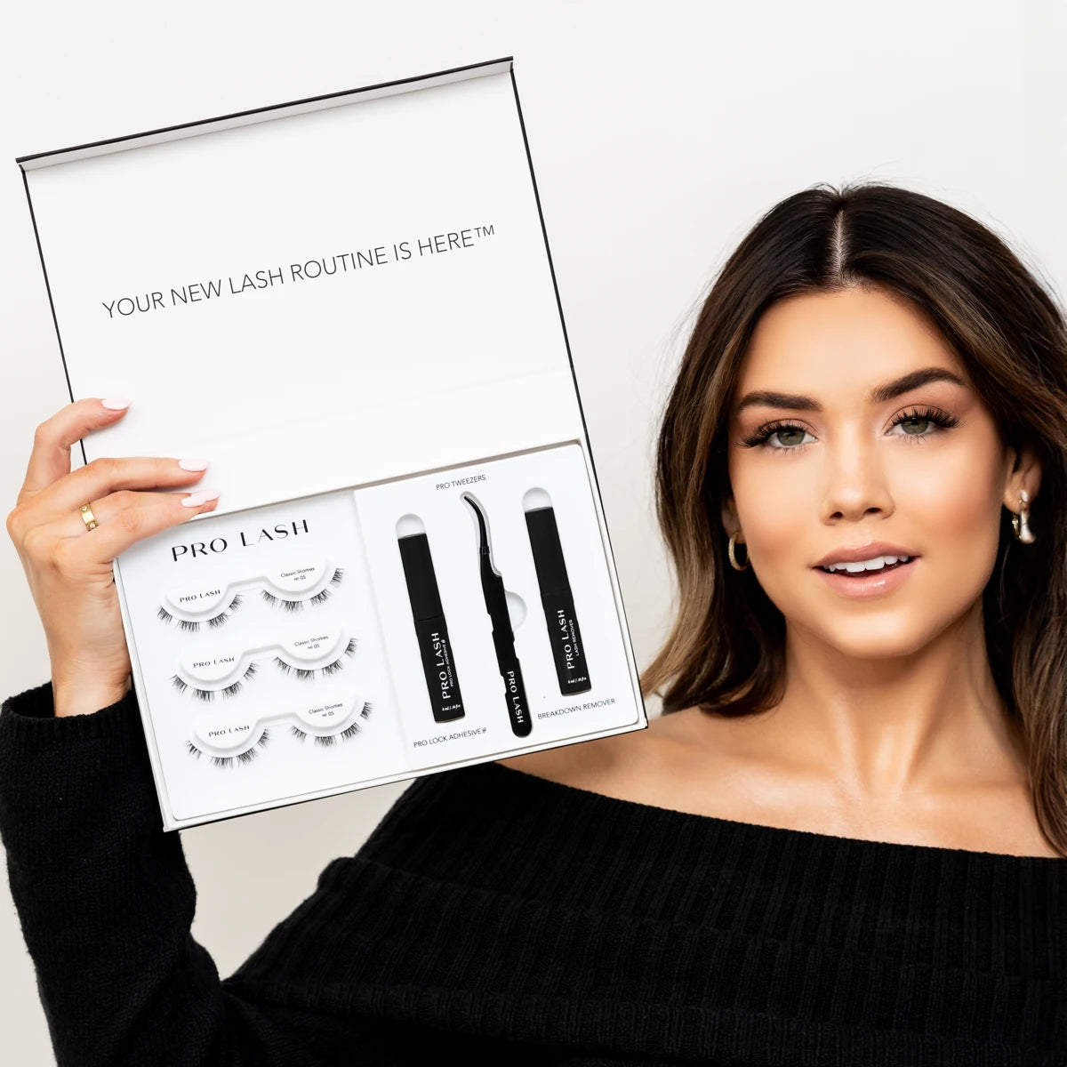 Best eyelash extension kit displayed by a woman holding an open Pro Lash box with lashes, adhesive, remover, and tools.