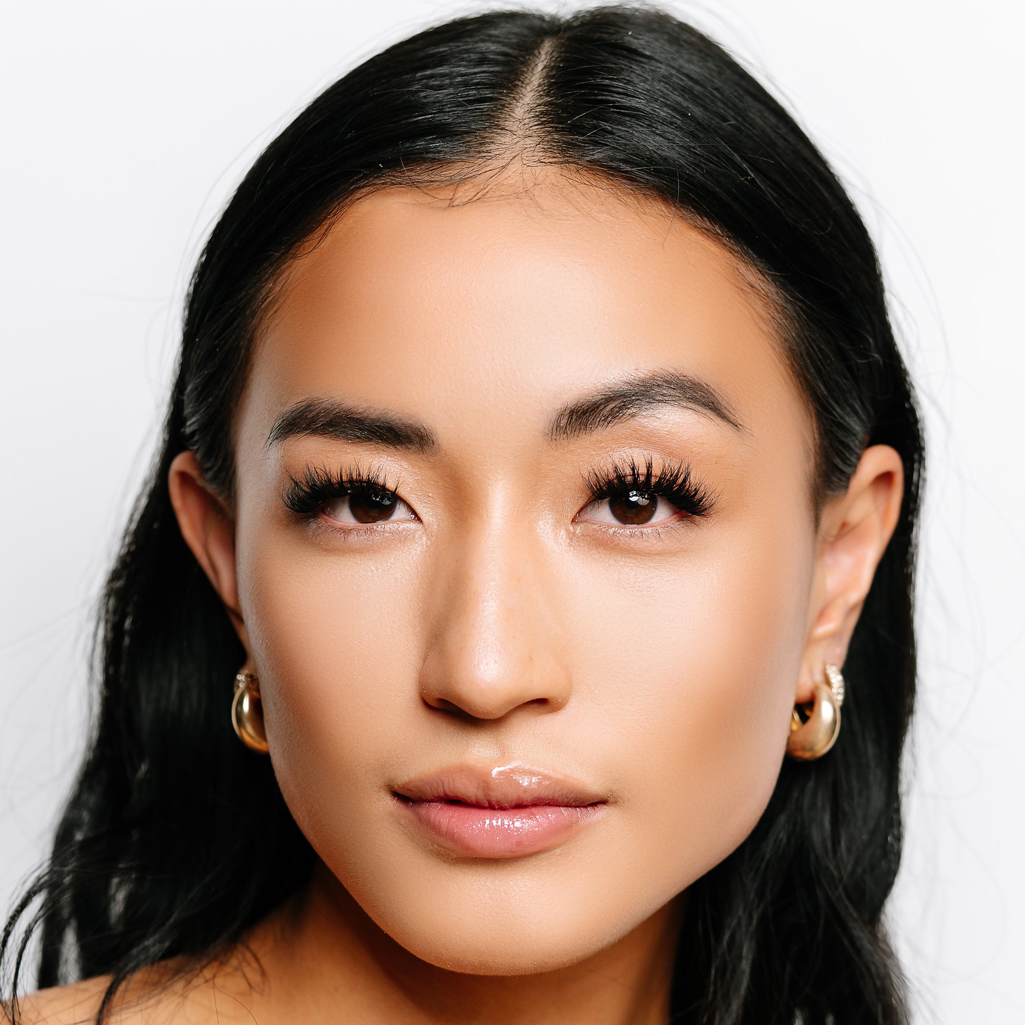 Feather lashes on model with long black hair, featuring soft layered volume and wispy texture for a lifted, eye-opening effect