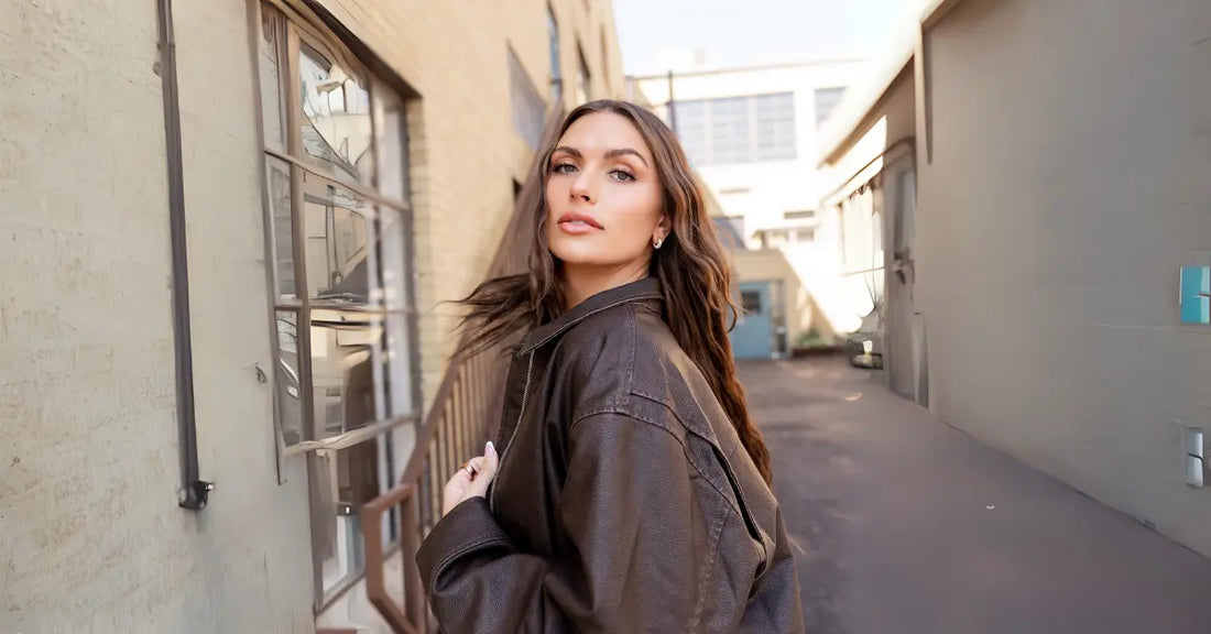 Volume Eyelash Extensions worn by stylish woman in brown jacket walking down urban alleyway.
