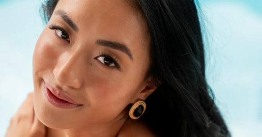 Best curly false lashes on a smiling woman with voluminous lashes and bold brows against a bright background.