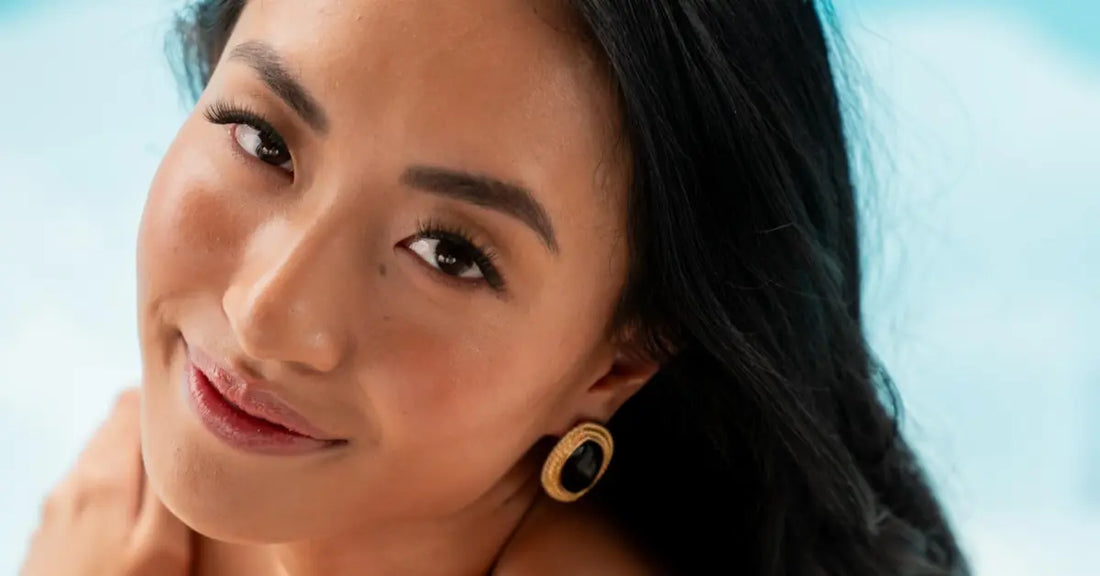 Best curly false lashes on a smiling woman with voluminous lashes and bold brows against a bright background.