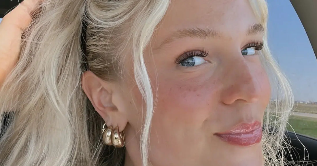 Classic eyelash extensions enhancing a woman’s blue eyes with a soft, natural curl and subtle everyday volume.