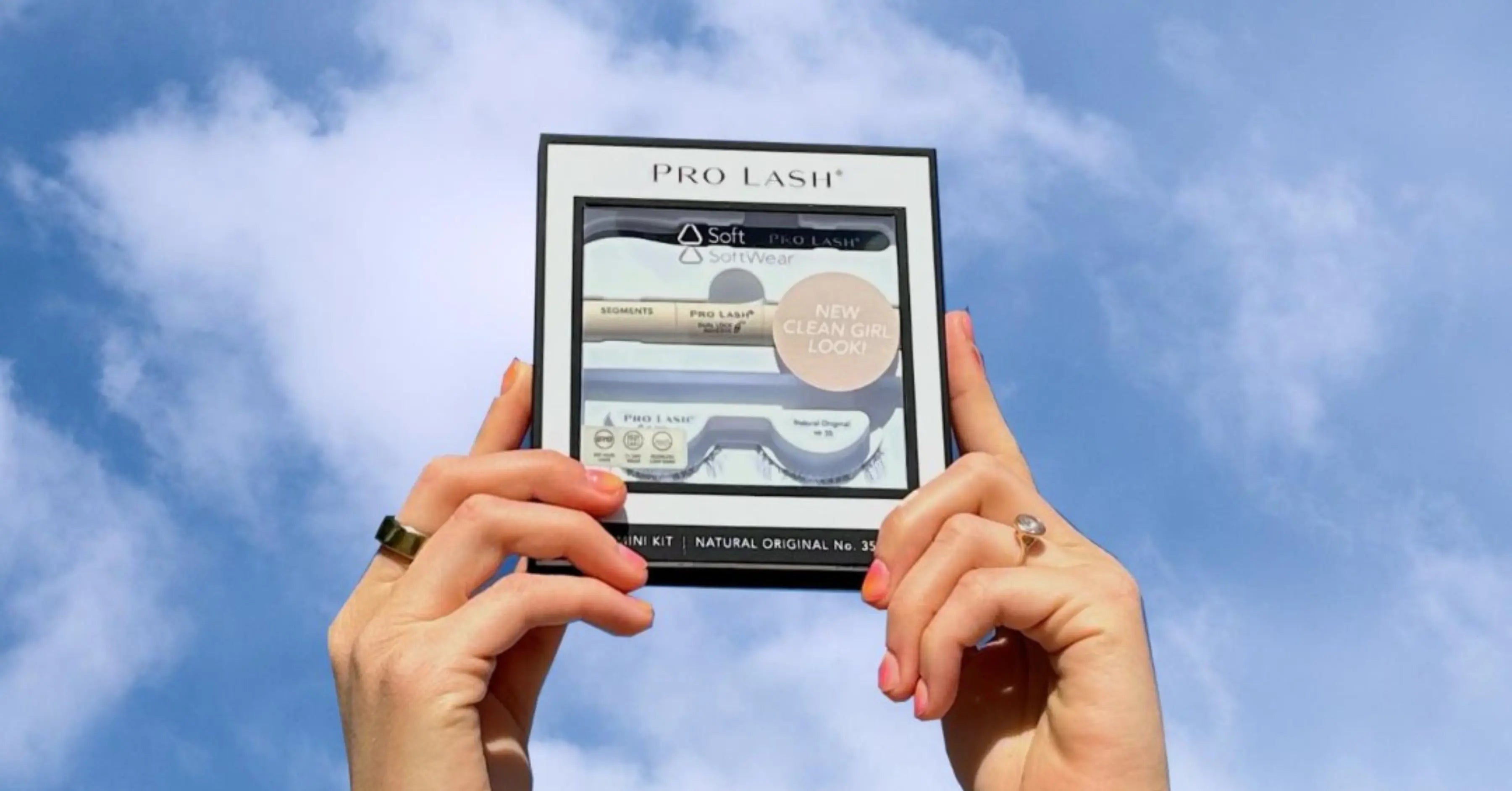 Lash extension tools featured in Pro Lash packaging held against a blue sky, showcasing applicator and lash set included in the kit.