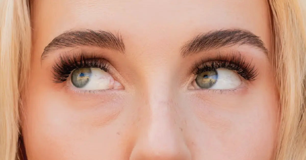 Lash extensions with a full, voluminous look shown on a close-up of eyes looking upward