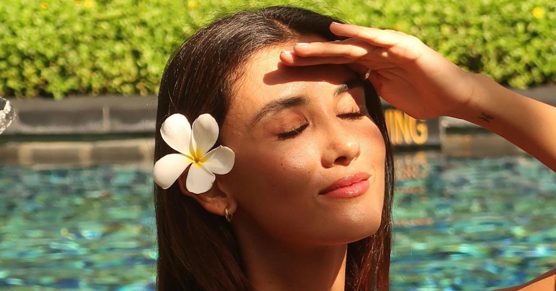 Long-lasting lash extensions on a sunlit model by a pool, showing a natural glossy look with relaxed, beachy vibe.