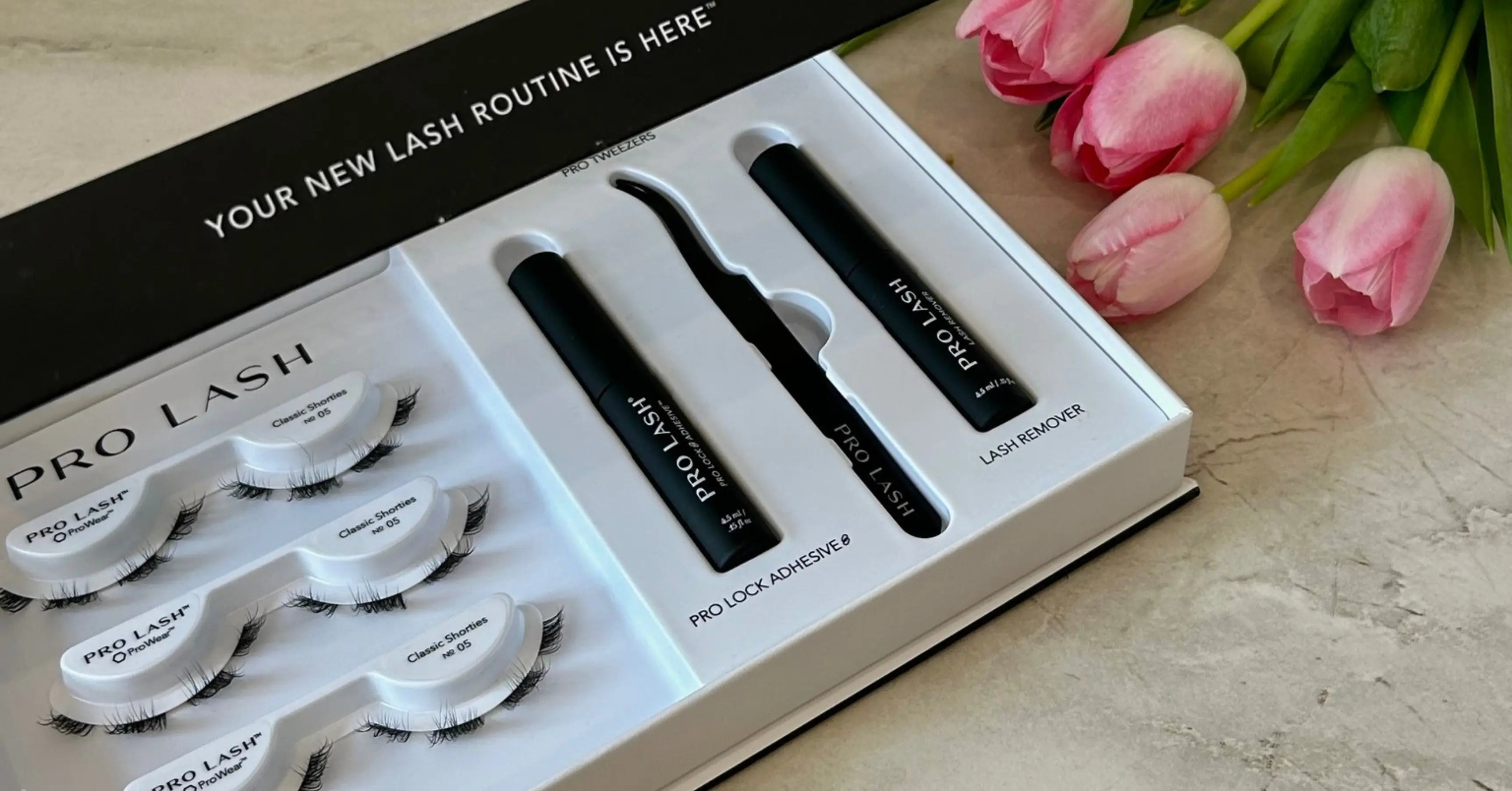 Mixed full set lashes in Pro Lash starter kit displayed in open box with Classic Shorties, Pro Lock adhesive, tweezers, and lash remover beside pink tulips