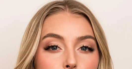 At-home lash extensions on blonde woman with voluminous, curled lashes and soft glam eye makeup.