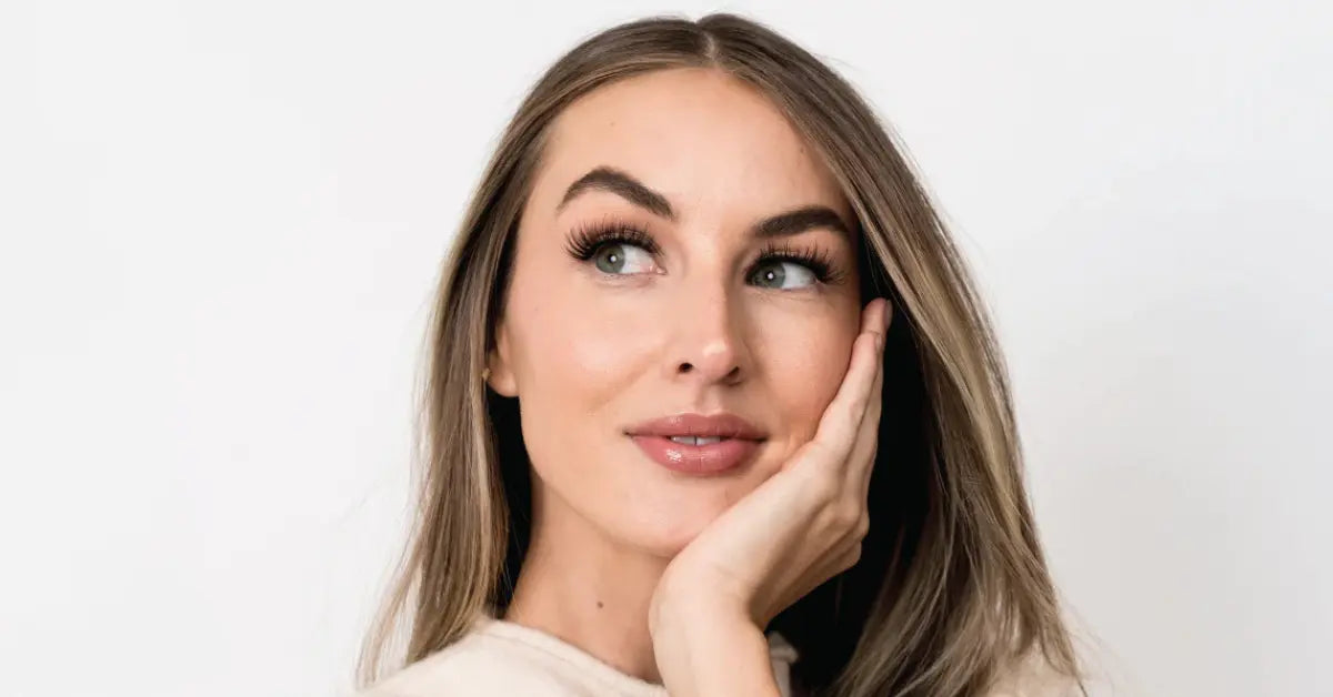 Natural lash extensions on a woman looking upward with full, defined lashes and smooth makeup.