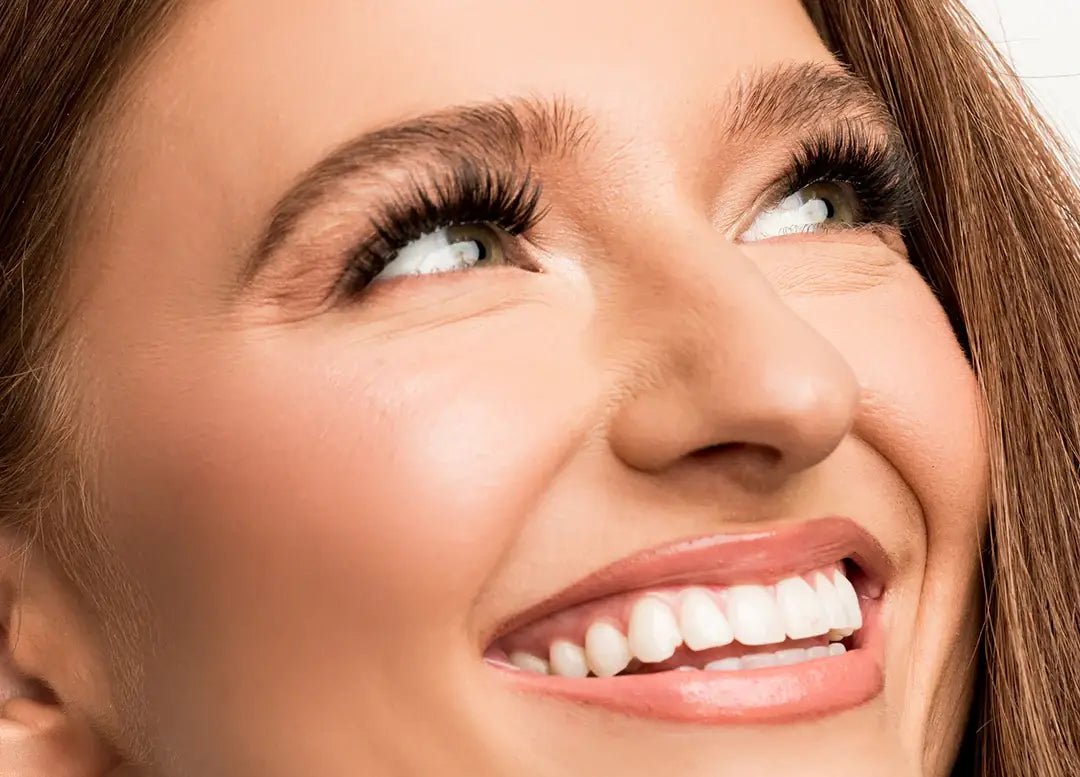 volume lashes on smiling woman with long thick eyelashes looking upward