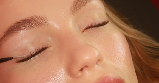 Lash extensions being applied with a precise brush to closed eyelid during a lash treatment