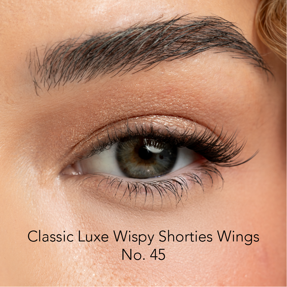 Close-up of an eye with false eyelashes labeled 'Classic Luxe Wispy Shorties Wings No. 45'.