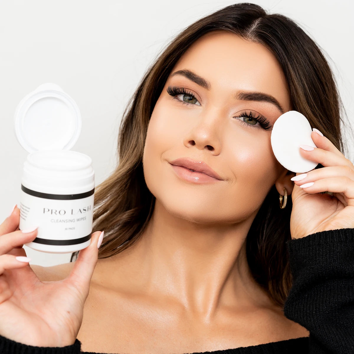 Lash kit at home featuring Pro Lash cleansing wipes and a round pad applied by a woman for lash care.