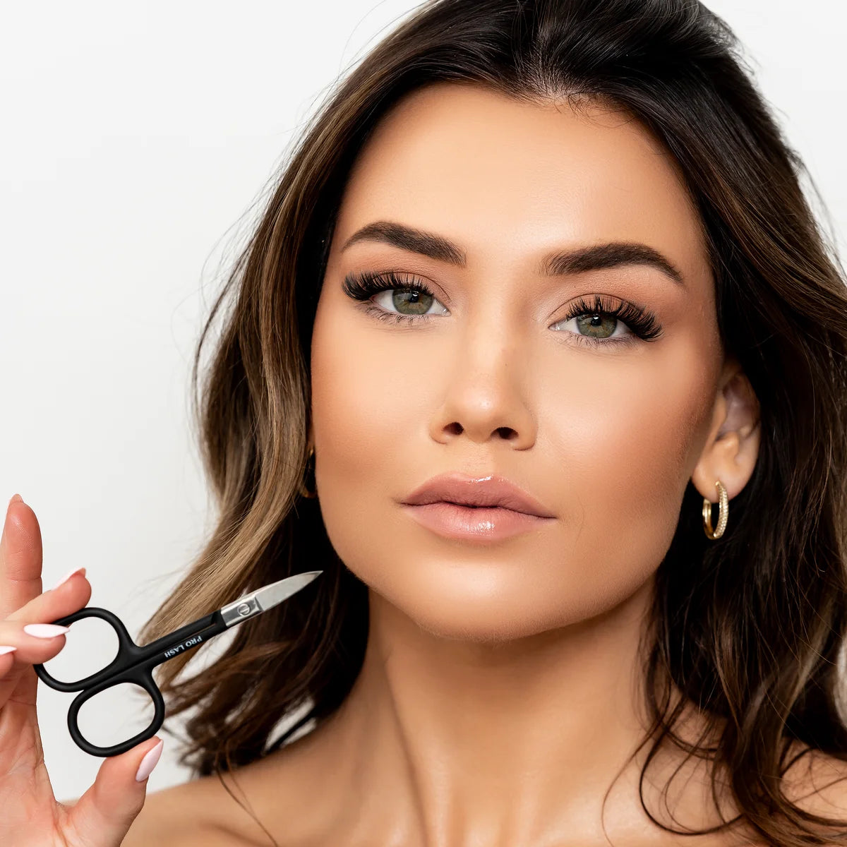 DIY eyelash extensions application shown with woman holding Pro Lash scissors and wearing voluminous false lashes.