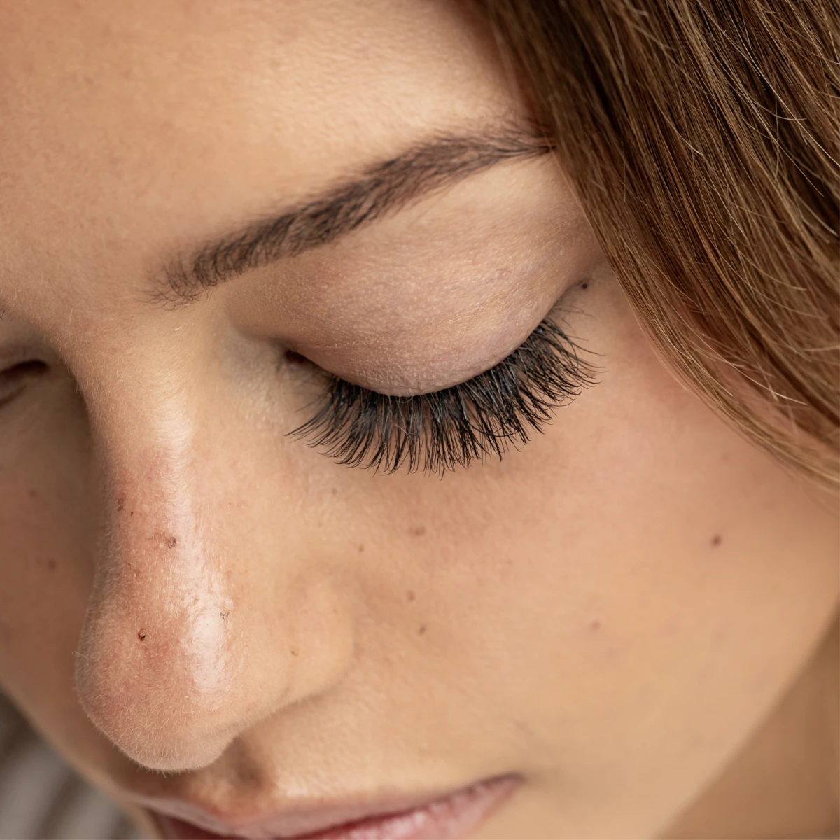 Eyelash extensions on closed eye showing full, voluminous lashes applied to upper lash line with natural finish and seamless blend